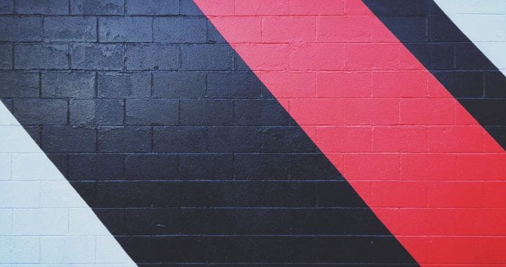 Black and red abstract lines painted on a gray brick wall